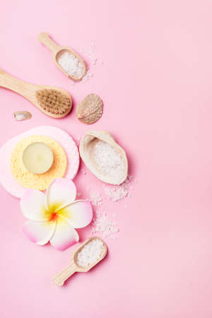 Sea Salt Aroma Candles Face Sponges and Bamboo Face Brush Plumeria Flower and Small Bamboo Scoops with Salt Pink Background Copy space SPA Wellnessの写真素材