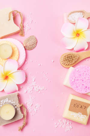 Sea Salt Aroma Candles Face Sponges and Bamboo Face Brush Plumeria Flower Natural Soap Pink Background Copy Space SPA Frame Top View Wellnessの写真素材