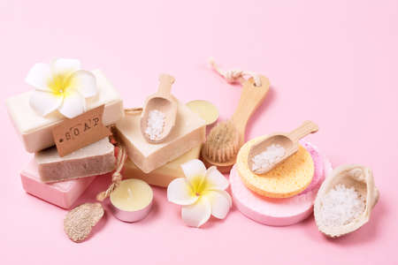 Sea Salt Aroma Candles Face Sponges Bamboo Face Brush Plumeria Flower Natural Soap Scoop with Salt Shell Pink Background SPA concept Top View Horizontal Wellnessの写真素材