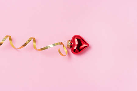 Red Heart Shaped Christmas Ornament with Golden Ribbon Pink Background Horizontal Christmas or St. Valentine Cardの写真素材