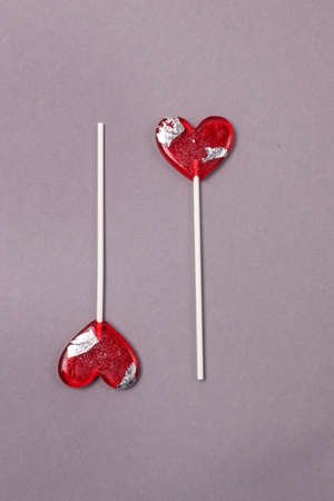 Two Red Lollipops in Hearts Shape on Gray Background C Love Concept with Candy Valentine Day Verticalの写真素材