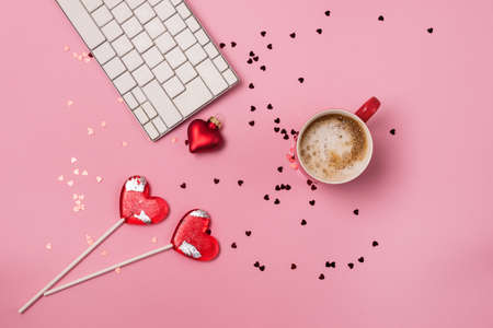 Red Cup of coffee White Keyboard Sparkling Red Confetti Two Lollipop in shape of Heart Pink background Blogger Workplace on Valentine's Day Holiday conceptの写真素材