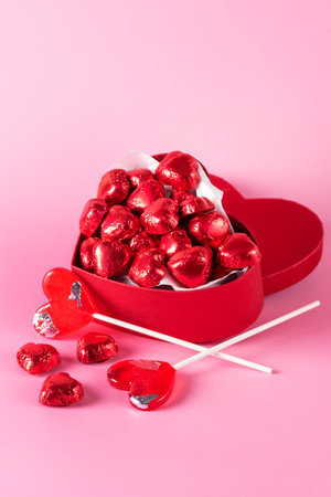 Beautiful Red Chocolate Hearts Candies in Red Box and Red Lollipop Shape of Heart on Pink Background St Valentine Day Background Dessert Copy Space Verticalの写真素材