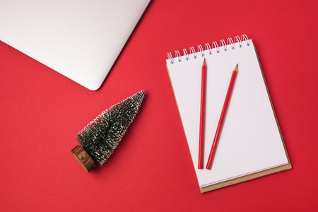 Christmas Holiday Business Concept Blank Notebook Small Christmas Tree Laptop Red Pencils Top Above Overhead View Flat Lay Red Background Horizontalの写真素材