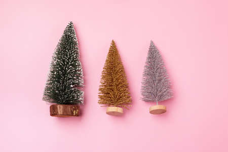 Three Small Christmas Trees on Pink Background Green Silver and Gold Christmas Tree Horizontalの写真素材