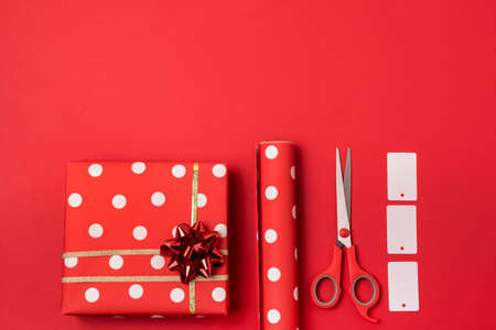 Flat lay Composition with Christmas gifts Red Dotted Wrapping Paper and Scissors on Red Background Horizontal Copy Space Holiday Backgroundの写真素材