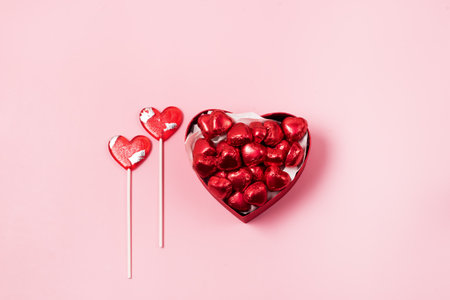 Beautiful Red Chocolate Hearts Candies in Red Box and Red Lollipop Shape of Heart on Pink Background St Valentine Day Background Dessert Verticalの写真素材