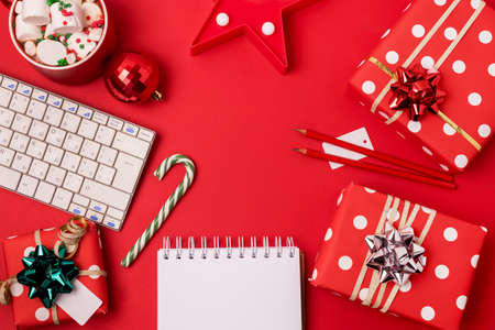 Workspace with keyboard and christmas gift and candy cane on red background flat lay top view, copy space Business christmas holidays concept holiday online shoppingの写真素材