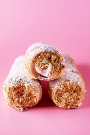 Three Tasty Homemade Pastry Tubes with Cream on Pink Background Selective Focus Sweet Tube with Whipped Cream Close Upの写真素材