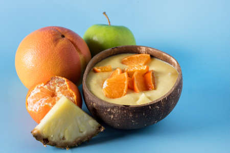 Healthy Smoothie from Banana Pineapple and Citrus in the Coconut Shell Bowl Healthy Summer Breakfast Blue Background Copy Spaceの写真素材