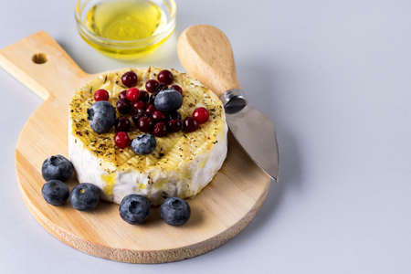 French Camambert Cheese with Berry and with Honey on Wooden Cheese Board Blue Background Horizontalの写真素材