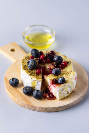 French Camambert Cheese with Berry and with Honey on Wooden Cheese Board Blue Backgroundの写真素材