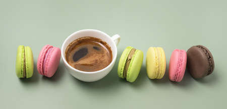 Macarons of Different Color and Cup og Coffee on Green Background Long