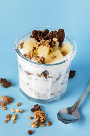 Glass of Diet Dessert with Yogurt Muesli or Granola Diet Cookies with Oatmeal and Fruit Blue Background Healthy Diet Breakfast Verticalの写真素材