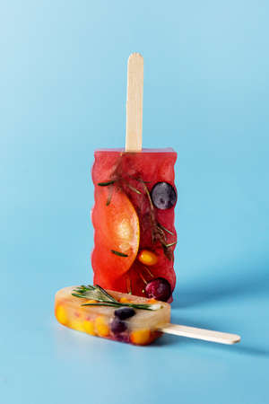 Natural Berry and Fruit Tea Flavor Popsicles on Blue Background Summer Refreshing Delicious and Healthy Treat or Desserts Popsicle for Tea Verticalの写真素材