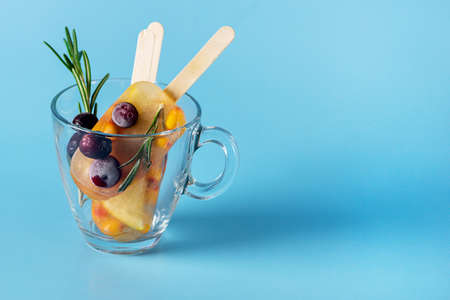 Healthy Testy Homemade Tea ice in Glass Tea Cup with Citrus Berry and Rosemary Blue Background Copy Spaceの写真素材