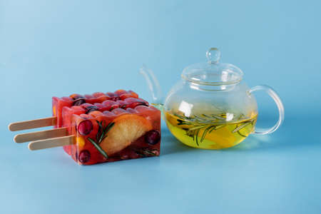 Natural Berry and Fruit Tea Flavor ice on Blue Background Summer Refreshing Delicious and Healthy Treat or Desserts ice for Tea Horizontal Glass Teapotの写真素材