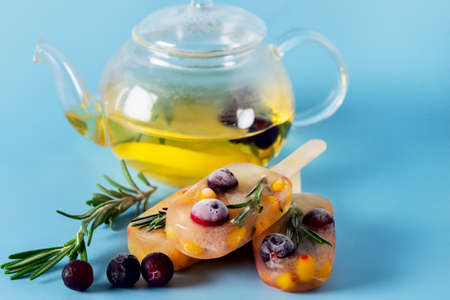 Frozen Refreshing Drinks Cold ice Frozen Sweet Citrus Lemon Tea with Rosemary and Berry Blue Background Copy Space Glass Teapotの写真素材