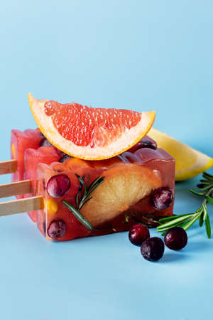 Frozen Refreshing Summer Cocktail ice Recipe Cold Sweet Berry and Citrus Tea with Rosemary Blue Background Verticalの写真素材