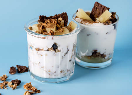 Healthy Breakfast: Yogurt Parfait With Granola Pineapple and Oatmeal Cookies Breakfast in Glass Blue Backgroundの写真素材