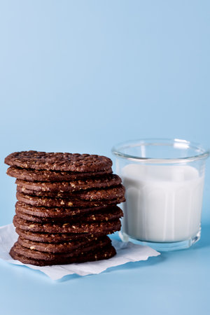 Glass of Milk and Oatmeal Chocolate Cookies on a Blue Background Verticalの写真素材