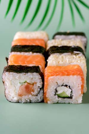 Sushi Roll (Philadelphia) with Salmon Cream Cheese on Fake Monstera Leaf on Green Background Sushi Menu Japanese Food Verticalの写真素材