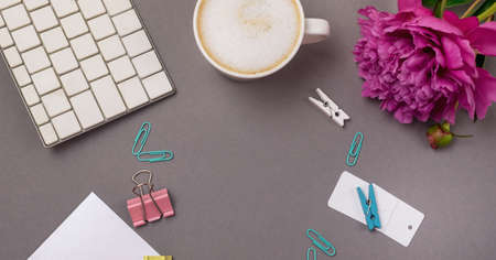 Feminine Workspace with Bunch of Pink Peony Computer Keyboard Paper Cup of Coffee Gray Background Business or Blogger Concept Flat Lay Longの写真素材