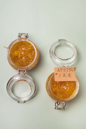 Two Glass Jars with Jam from Apricots on Green Background Top View Horizontalの写真素材