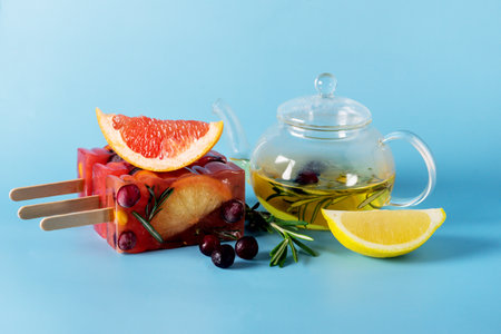 Frozen Refreshing Drinks Cold ice cream Frozen Sweet Citrus Lemon Tea with Rosemary and Berry Blue Background Copy Space Glass Teapotの写真素材