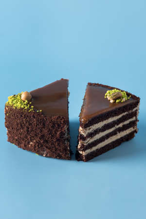 Homemade Chocolate Cake with Vanilla Cream on a Blue Background Decorated with Nuts Tasty Dessert Verticalの写真素材