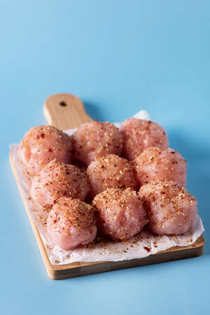 Homemade Small Fresh Chicken Meatballs with Spice on Wooden Tray Blue Background Himemade Semi Finished Product Verticalの写真素材