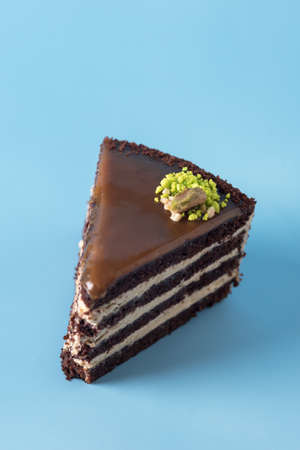 Homemade Chocolate Cake with Vanilla Cream on a Blue Background Decorated with Nuts Tasty Dessert Verticalの写真素材