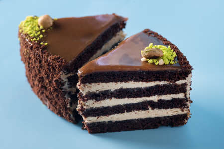 Homemade Chocolate Cake with Vanilla Cream on a Blue Background Decorated with Nuts Tasty Dessert...