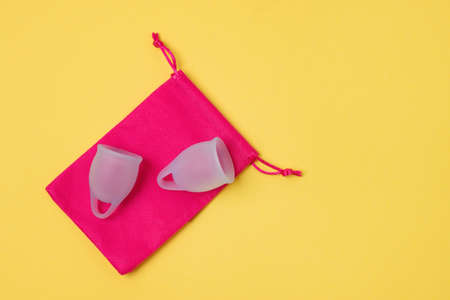 Two Blue Menstrual Cup on Pink Bag on Yellow Background Woman's Health and Environmentally Friendly Feminine Hygiene Product Concept Copy Spaceの写真素材