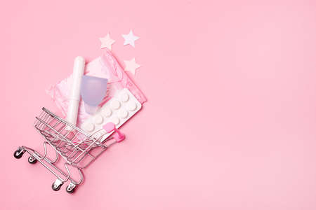 Shopping Cart with Menstruation Period Accessories on Pink Background Sanitary Pads Tampons Menstrual Cup and Pills Horizontal Copy Spaceの写真素材