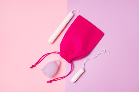 Blue Menstrual Cup Pink Bag Tampons on Pink and Lilac Background Woman's Health and Environmentally Friendly Feminine Hygiene Product Concept Top Viewの写真素材