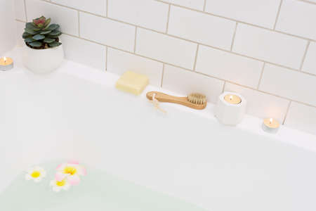 Bathtub with Plumerria Flowers and Inflatable Flamingo Toy Ring with Drink Bamboo Face Brush Home SPA Concept Relaxの写真素材