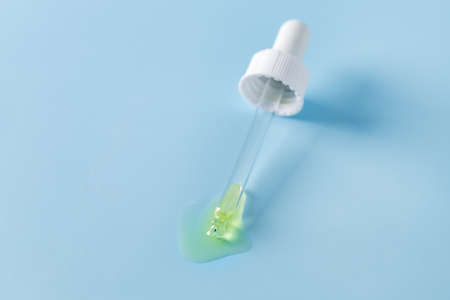 White Pipette on Blue Background Drops of Serum Horizontal Copy Space Beauty Conceptの写真素材