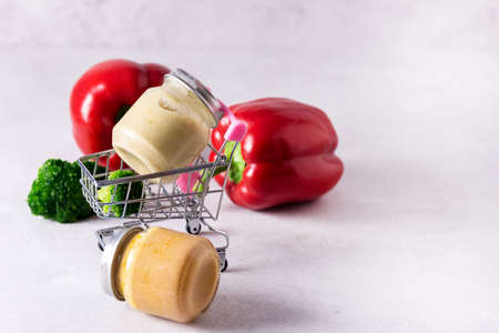Glass Jars with Natural Baby Food on the Light Gray Background Vegetable Puree with Broccoli and Red Pepper Copy Spaceの写真素材