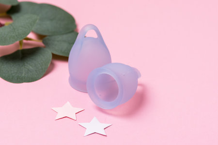Women Health Concept Zero Waste Blue Menstrual Cups Fake Green Plant Leaves Background Alternative Reusable Product for Female Hygiene during Periods Minimalisの写真素材