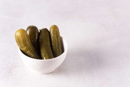 Small tasty pickled cucumbers Traditional recipe served in a ceramic white bowl gherkins gray background place for textの写真素材