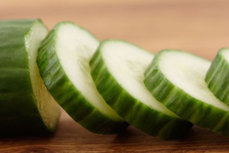 Sliced cucumber on a wooden cutting board.の写真素材