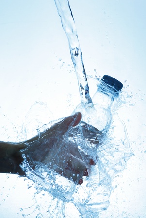 Water bottle in hand, in a spray of water dropletsの写真素材