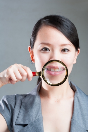 Portrait of lovely young woman with magnifying glass showing her white teethの写真素材