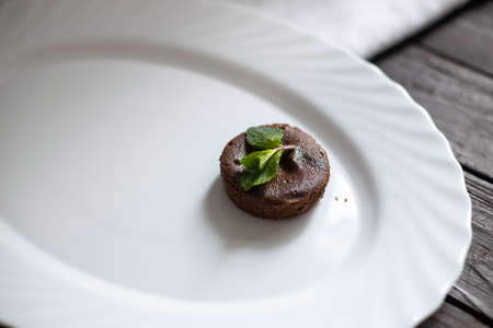 Chocolate brownie, fondant, on white plate, white linen and dark brown wood tableの写真素材