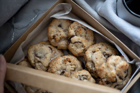 Box of chocolate chip cookies with Christmas lights behind, gray linen backgroudの写真素材