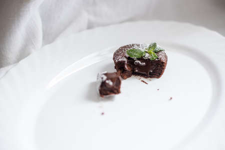 Chocolate fondant cut in half on white oval dish with mint leaves onの写真素材