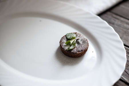Chocolate brownie, fondant, on white plate, white linen and dark brown wood tableの写真素材
