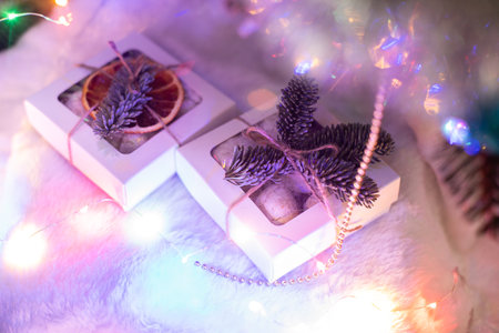 White square boxes decorated with pine branches and neon lights around, Christmas gifts, Handmade decoration, family holidaysの写真素材