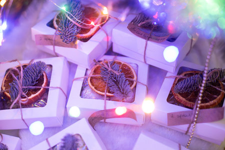 Christmas presents with neon lights around with fir branches and dried orangeの写真素材